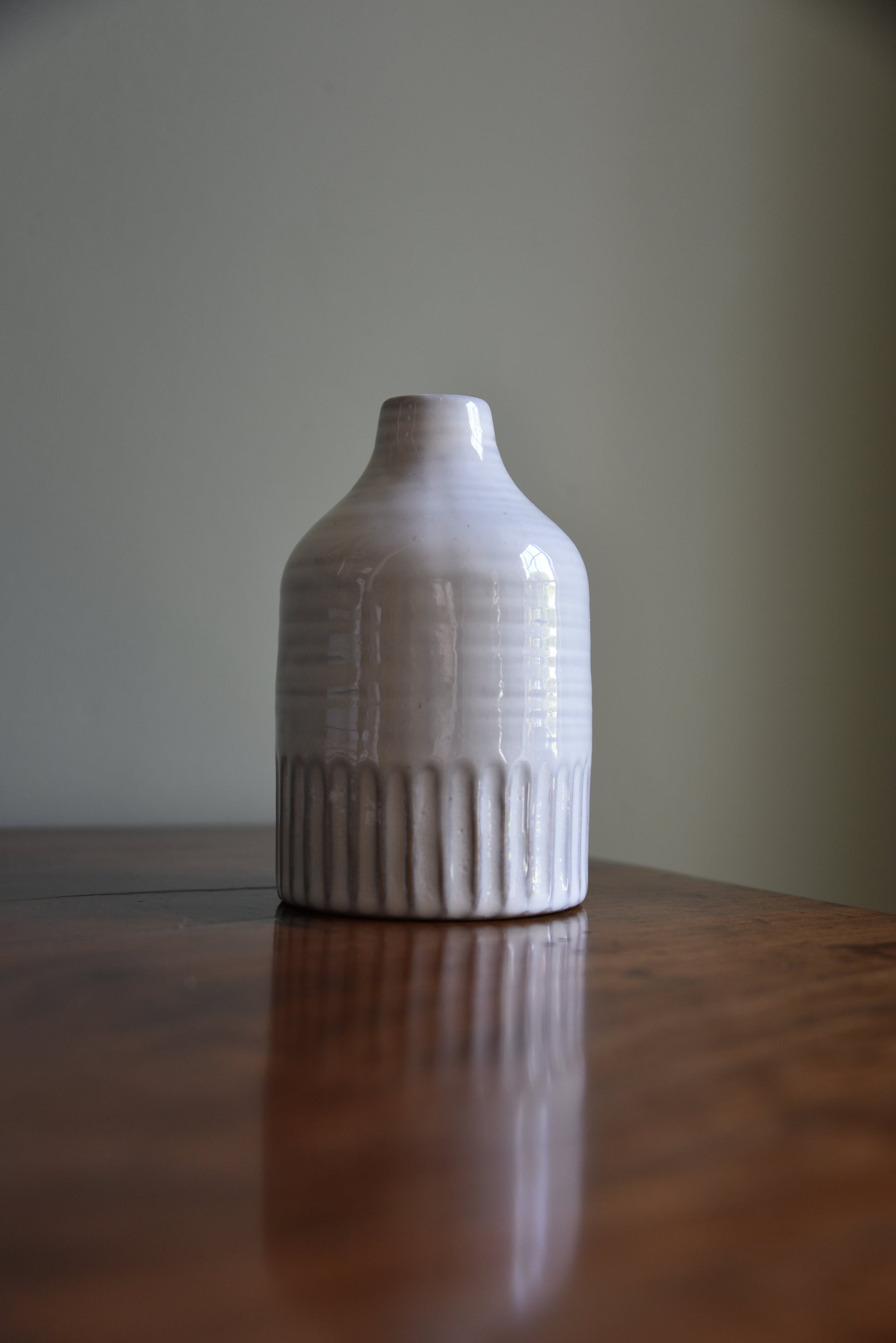 Close-up of a ceramic bottle vase on wooden table on a neutral background
