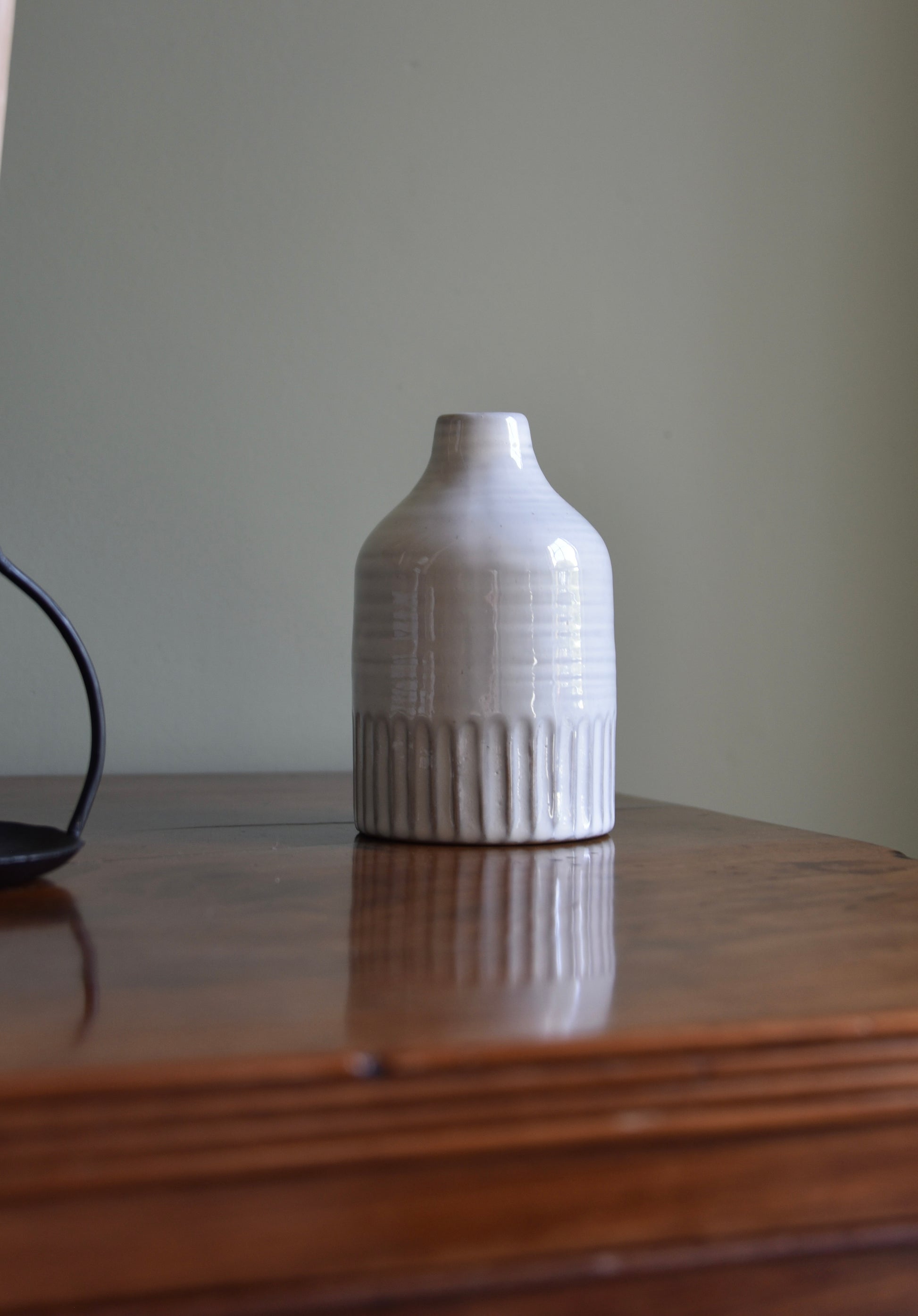 White textured vase on a wooden surface with a plain background