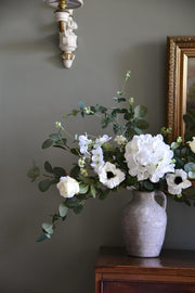 Close up of white hydrangeas, cosmos, roses and wild eucalyptus styled on a wooden table