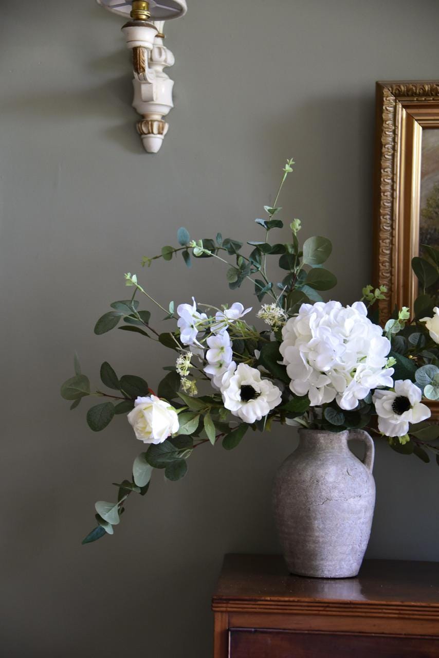 Close up of white hydrangeas, cosmos, roses and wild eucalyptus styled on a wooden table