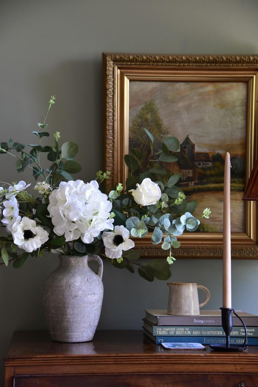Close up of white hydrangeas, cosmos, roses and wild eucalyptus styled on a wooden table