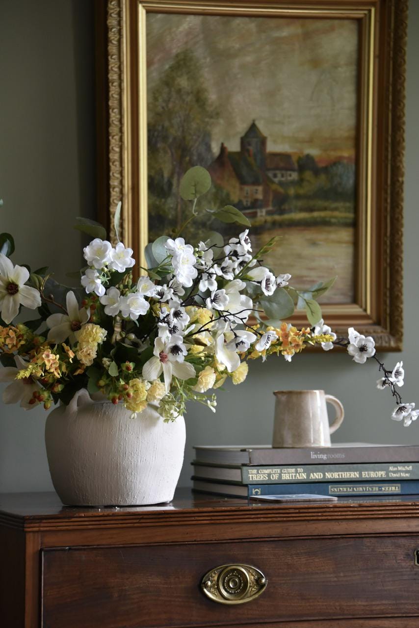 Large Ivory and Yellow Flower Arrangement including white blossom, yellow catmint flowers, stephanotis, magnolias, yellow carnations and green eucalyptus  on wooden table and antique painting in background